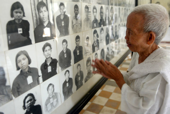 A Cambodian woman reacts and gestures as she looks at portrait photos of victims of the Khmer Rouge regime displayed for tourists at the Tuol Sleng Genocide Museum in Phnom Penh on June 4, 2013.