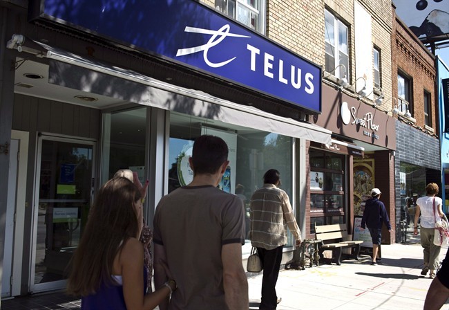 Pedestrians walk by a Telus store in Toronto, Thursday, August 15, 2013. 