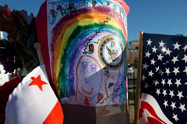 Across the street from the Washington Navy Yard, a child's drawing, the U.S. and D.C. flags, and a bouquet of flowers are taped to a post in a makeshift memorial to the victims two days after a gunman killed twelve people and was killed himself inside the Navy Yard in Washington, on Wednesday, Sept. 18, 2013. 