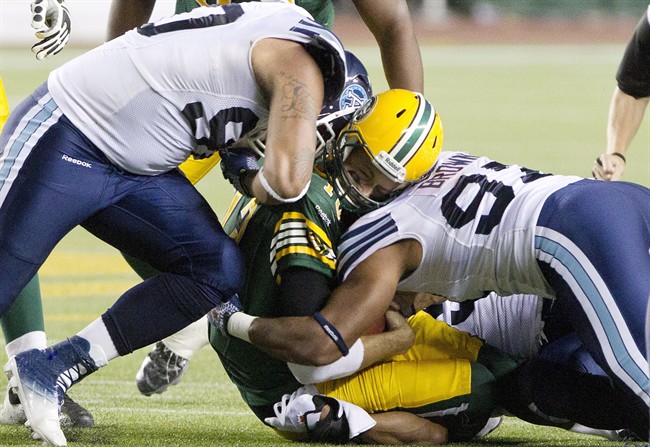 Toronto Argonauts' Cleyon Laing (90) and Ivan Brown (97) hit Edmonton Eskimos quarterback Mike Reilly (13) during first half action in Edmonton, Alta., on Saturday September 28, 2013. Reilly has been diagnosed with a concussion, the team said on Sunday.Reilly sustained a helmet-to-helmet hit on this play in the first quarter of Saturday's 34-22 loss at home to the Toronto Argonauts and was evaluated before staying in the game for one more play.
