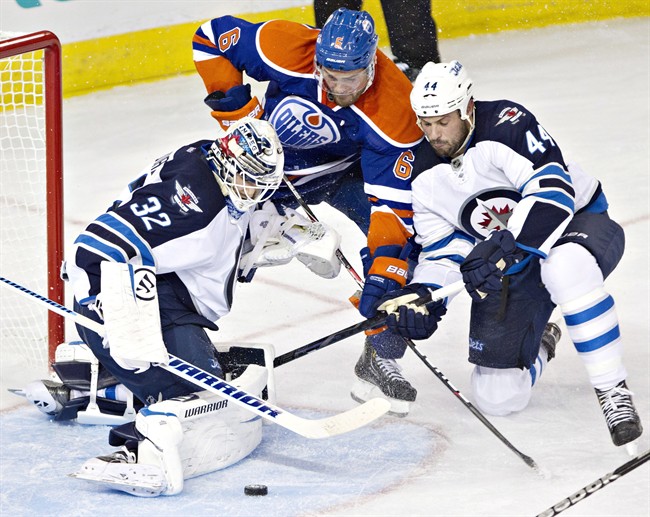 Winnipeg Jets goalie Edward Pasquale (32) makes the save as Zach Bogosian (44) and Edmonton Oilers Jesse Joensuu (6) battle for the rebound during third period NHL pre-season hockey action in Edmonton, Alta., on Monday September 23, 2013. THE CANADIAN PRESS/Jason Franson.