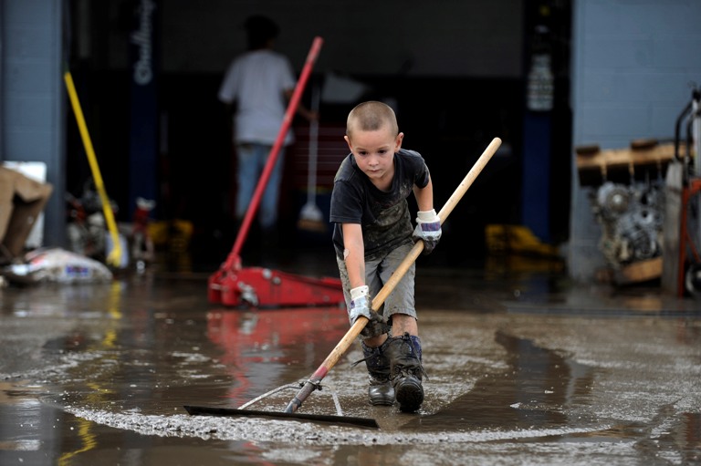 Michael Adamson, 5, uses a squeegee to clean the mud left by flood waters in front of T&M Automotive on Boston Ave in Longmont, Colorado on September 14, 2013. Clean up began on Saturday in downtown Longmont following heavy flooding in previous days. (Seth McConnell/The Denver Post via Getty Images)