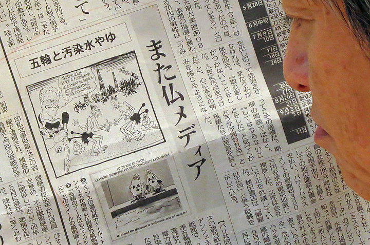 A man reads a Japanese local newspaper reporting cartoons published in a French newspaper, in Tokyo on September 12, 2013. Japan voiced anger September 12 over cartoons published in a French newspaper that took aim at the decision to award the 2020 Olympics to Tokyo despite the ongoing nuclear crisis at Fukushima.