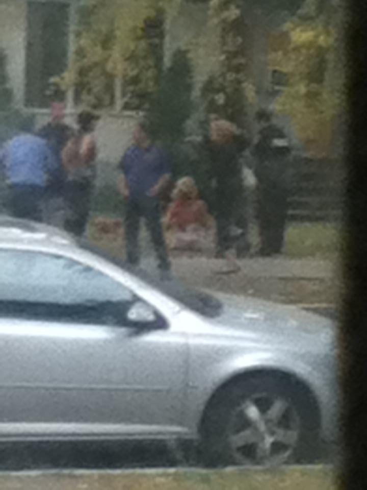 In an image from a camera phone, the woman who was assaulted can be seen sitting on the sidewalk.