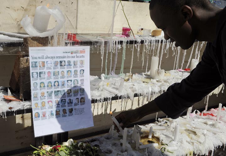 A Kenyan man lights a candle next to a list of the victims who were killed in the Westgate Mall massacre in Nairobi on September 30, 2013. 
