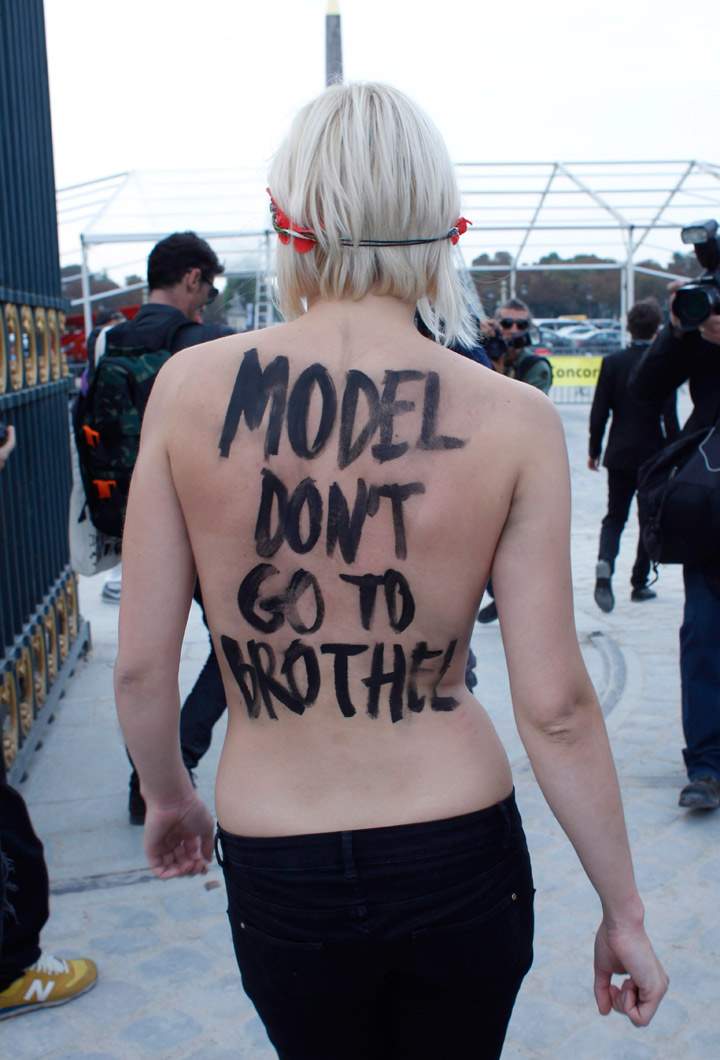 An activist of Femen, a feminist Ukrainian protest group, leaves the Tuileries Gardens after two of them were removed by security staff while disturbing the presentation of Nina Ricci's ready-to-wear Spring/Summer 2014 fashion collection Thursday, Sept. 26, 2013 in Paris.