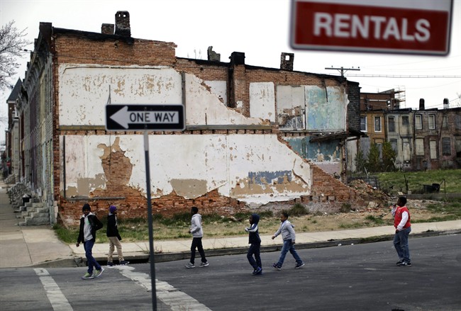 In this April 4, 2013 file photo, a group of boys walk past a partially collapsed row house in Baltimore.