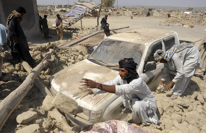 Pakistani survivors clear the debris of destroyed houses in the earthquake-devastated district of Awaran on September 25, 2013.