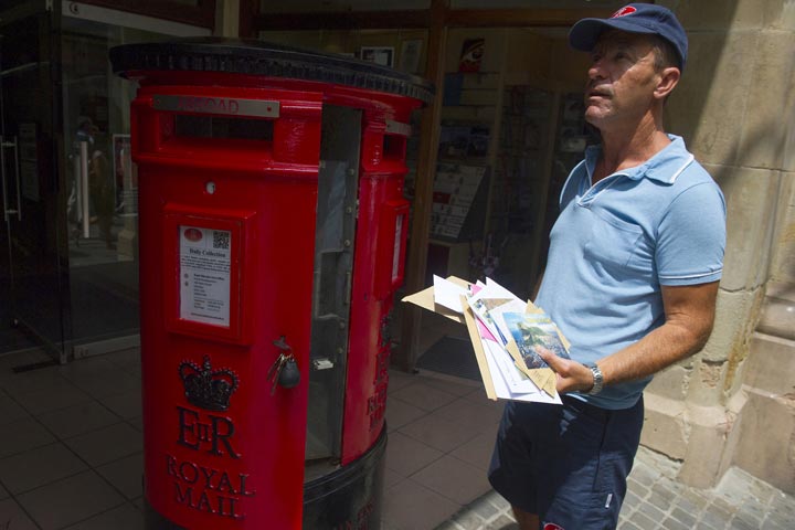 A Royal Mail employee gathers the contents of a mailbox in Gibraltar on August 13, 2013.