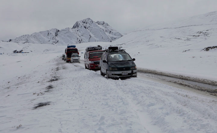 Vehicles pass the mountain along the road surrounded by snow covered fields on La Cumbre mountain on the outskirts of La Paz, Bolivia, of La Paz, Bolivia, Sunday, Aug. 25, 2013. The snow fall since Saturday night and early Sunday has affected the normal transit of vehicle through the mountains. (AP Photo/Juan Karita).