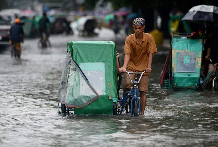 A pedicab driver wades through a flooded street in Manila on September 23, 2013. Monsoon rains worsened by Typhoon Usagi pounded the Philippines for the third day on September 23, causing floods and landslides that left six people dead and others stranded on rooftops, officials said.(Photo credit: Getty Images)
