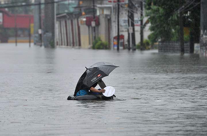 A resident using a innertube as a makeshift raft paddles through chest-deep floodwaters along a street in Manila on September 23, 2013, after torrential rains pounded Luzon island worsened by Typhoon Usagi.  (Photo credit: Getty Images)