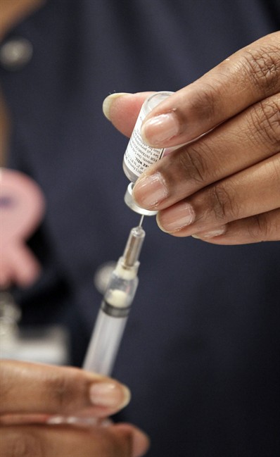 FILE - This Oct. 17, 2012 file photo shows a nurse loading a syringe of vaccine.