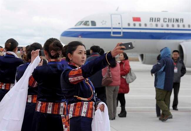 A Tibetan woman uses her cellphone to take photos of a flight that touched down at Yading airport, the world's highest-altitude civilian airport at 4,411 meters (14,471 feet)above the sea level, in Daocheng of Garzi Tibetan Autonomous Prefecture, known as "the last Shangri-La'', in southwest China's Sichuan province Monday Sept. 16, 2013. 