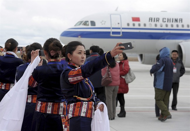 A Tibetan woman uses her cellphone to take photos of a flight that touched down at Yading airport, the world's highest-altitude civilian airport at 4,411 meters (14,471 feet)above the sea level, in Daocheng of Garzi Tibetan Autonomous Prefecture, known as "the last Shangri-La'', in southwest China's Sichuan province Monday Sept. 16, 2013. 