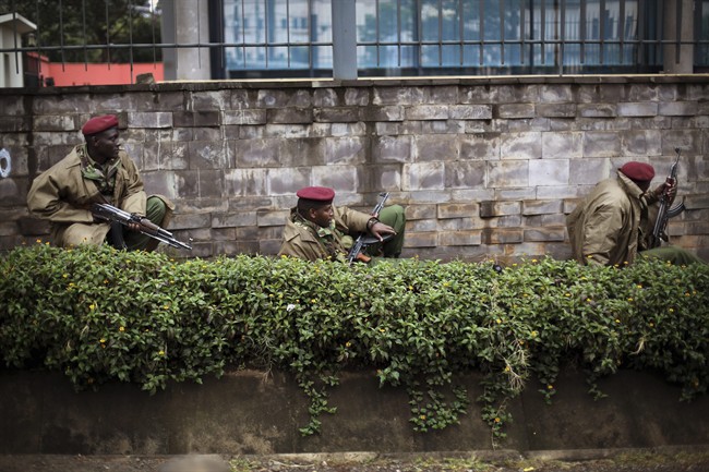 Kenya security forces are seen behind a wall outside the Westgate Mall in Nairobi, Kenya Monday morning, Sept. 23, 2013. Kenya's military launched a major operation at the upscale Nairobi mall and said it had rescued "most" of the hostages being held captive by al-Qaida-linked militants during the standoff that killed at least 68 people and injured 175. 