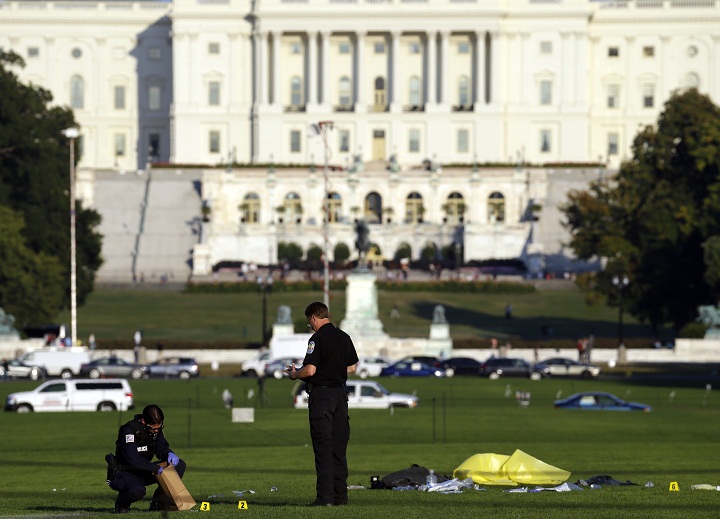 Police investigators gather evidence near where officials said a man set himself on fire, on the National Mall, Friday, Oct. 4, 2013, in Washington. 