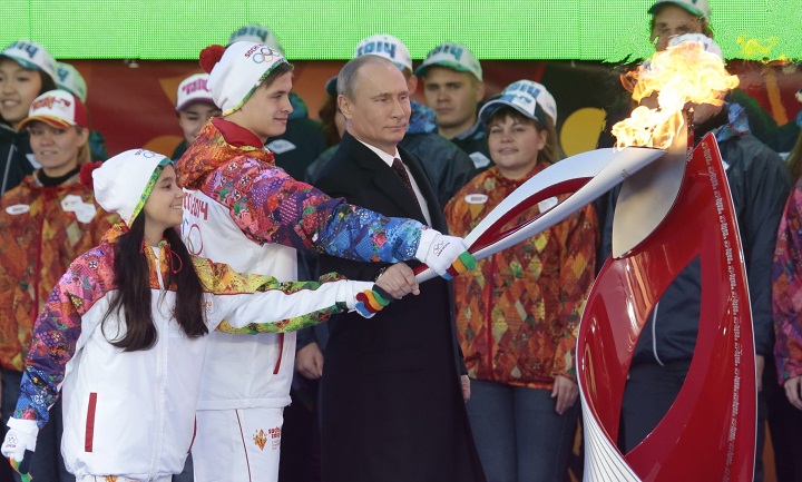 Russian President Vladimir Putin, a girl and a boy light an Olympic flame with a torch at Moscow's Red Square on Sunday, Oct. 6, 2013. Russian President Vladimir Putin has lit the Olympic flame on Red Square for the 123-day relay to Sochi for the Winter Games. 