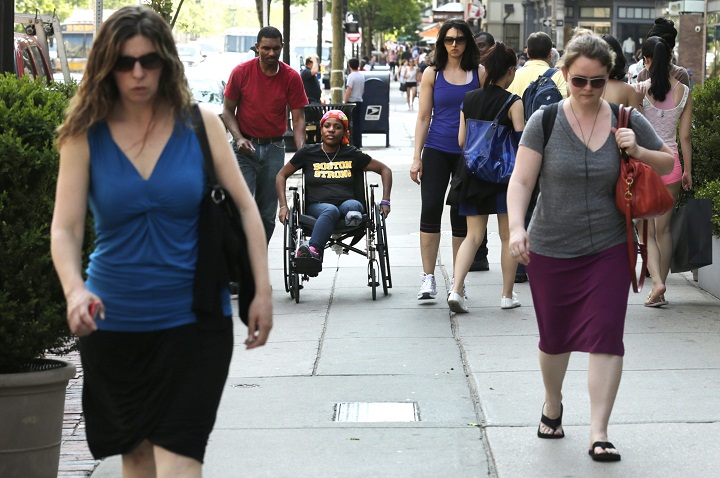 In this Friday, May 31, 2013 photo, Mery Daniel, a Boston Marathon bombing survivor, rolls her wheelchair down Boylston Street with her husband, Richardson Daniel, after visiting the explosion site where she lost most of her left leg in Boston. Daniel hopes to regain her independence and walk again. (AP Photo/Charles Krupa)