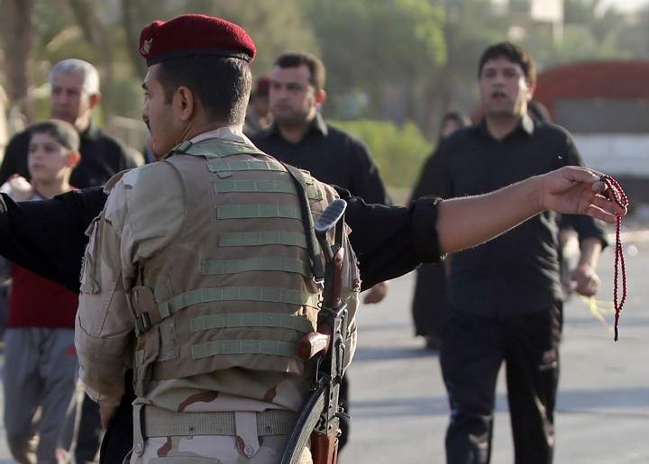 An Iraqi soldier mans a checkpoint on a road in Baghdads northern district of Kadhimiya on October 6, 2013 as Shiite pilgrims walk to a shrine to commemorate the death of Imam Mohammed al-Jawad, the ninth Shiite imam. Violence including an attack on Shiite pilgrims in Baghdad killed at least 73 people across Iraq on October 5, among them two journalists gunned down in the north, officials said. 