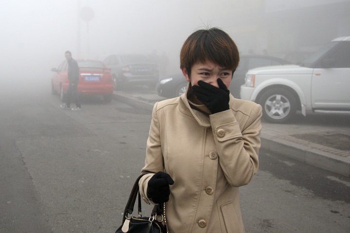 HARBIN, CHINA - OCTOBER 21: (CHINA OUT) A woman walks along a road as heavy fog engulfs the city on October 21, 2013 in Harbin, China. Heavy fog has been lingering in northeast China since Monday, disturbing the traffic, worsening air pollution and forcing the closure of schools.