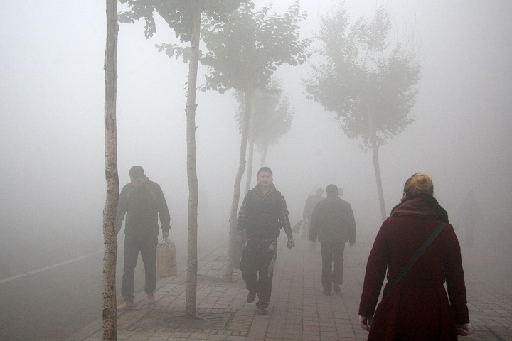 Pedestrains walk along a road as heavy fog engulfs the city on October 21, 2013 in Harbin, China.