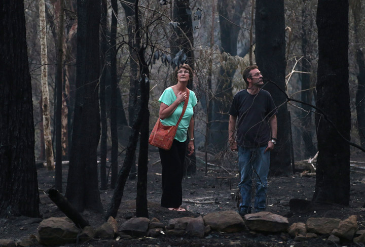 Jennifer Schweinsberg and her son David walk around the back yard of their destroyed family home in Sunny Ridge Drive in Winmalee 65 kilometers (40 miles) from Sydney in Australia, Tuesday, Oct. 22, 2013 after a wildfire swept through the street burning it and several other homes on Oct 18, 2013. (Photo credit: AP Photo)