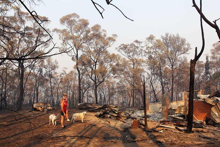 Melissa White assists her sister Christie Daschke at her home destroyed by bushfire on October 21, 2013 in Winmalee, Australia. (Photo credit: Getty Images)