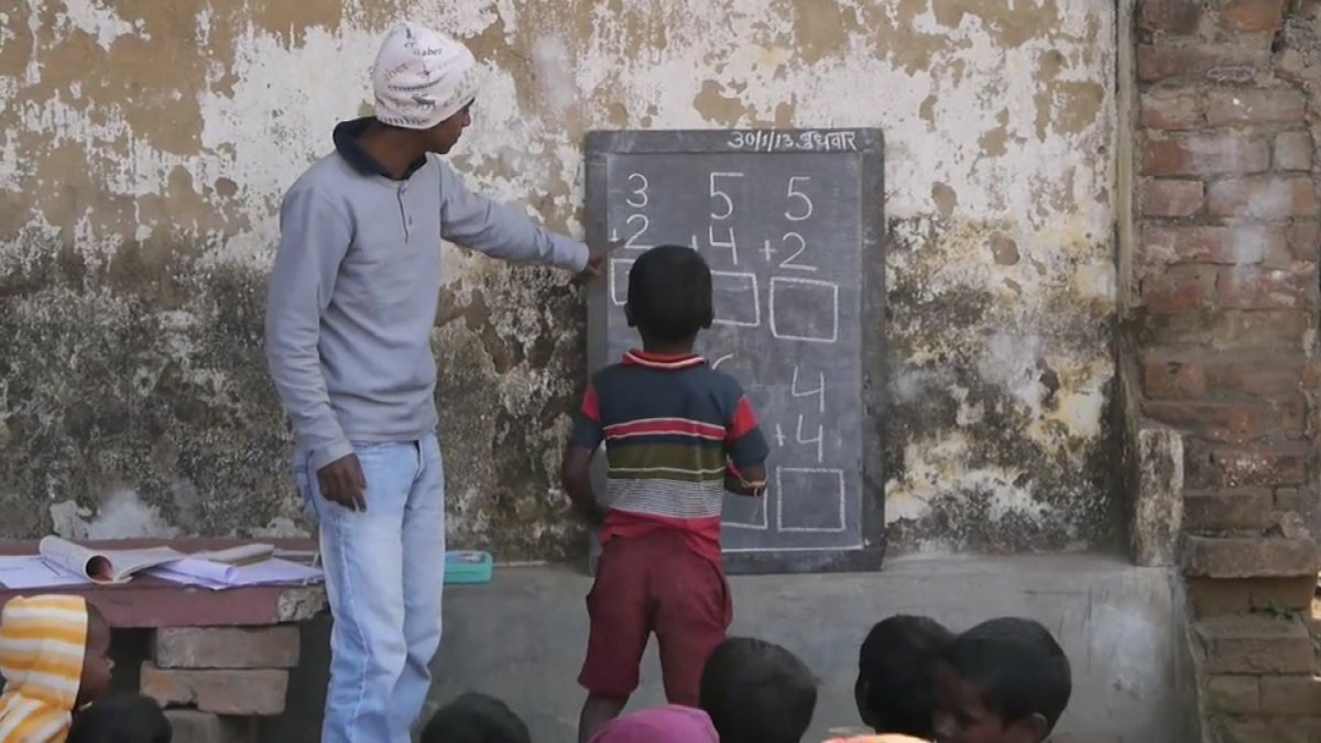 Children learn math during a break from working in brickfields in India.