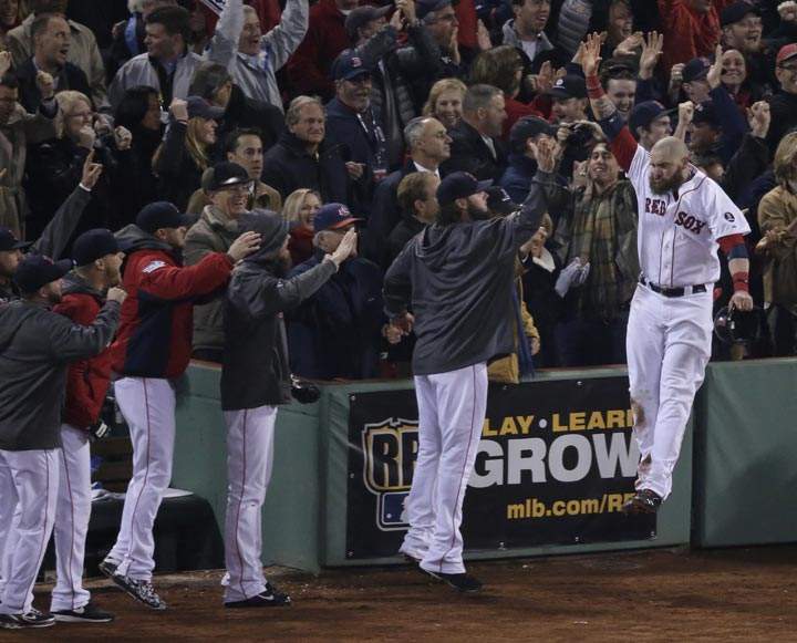 Boston Red Sox’s Jonny Gomes celebrates with teammates after scoring during the third inning of Game 6 of the World Series. (AP Photo/Charlie Riedel)