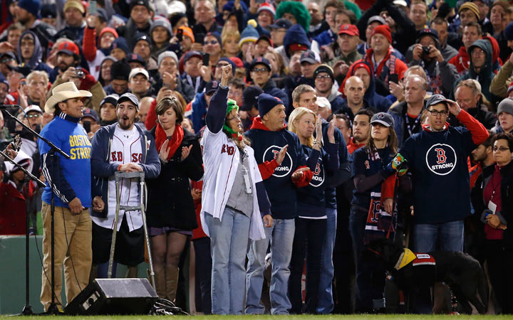 Carlos Arredondo, left, and Boston Marathon bombing survivor Jeff Bauman, second from left, stand with other Boston Marathon bombing survivors during the seventh inning stretch of Game 2 of baseball's World Series between the Boston Red Sox and the St. Louis Cardinals Thursday, Oct. 24, 2013, in Boston. (AP Photo/Elise Amendola).