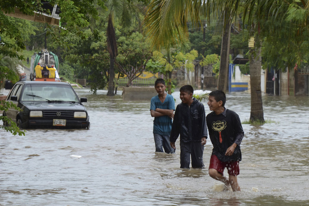Young men play in a flooded street in Acapulco, Mexico, Monday, Oct. 21, 2013. 