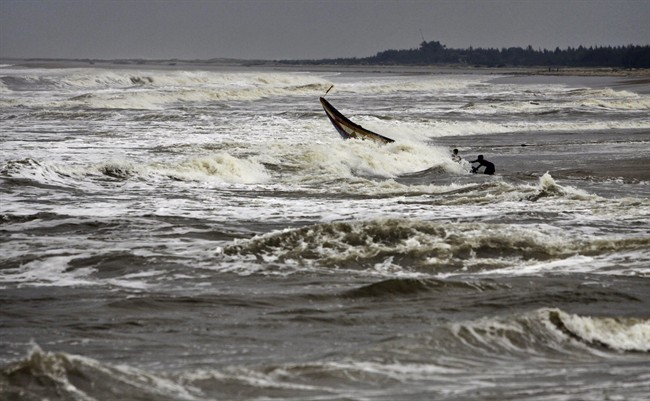 Indian fishermen try to balance their boat as they pull it out from the Bay of Bengal at Gokhurkuda in Ganjam district 215 kilometers (136 miles) away from the eastern Indian city of Bhubaneswar, India, Friday, Oct. 11, 2013.