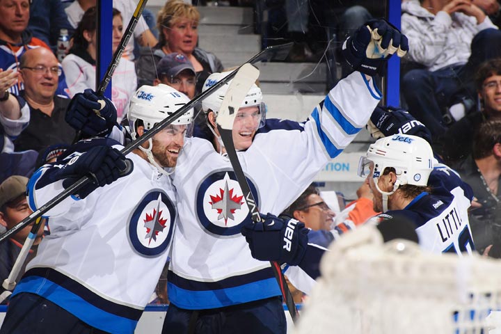 Jacob Trouba of the Winnipeg Jets celebrates scoring the Jets' fourth goal against the Edmonton Oilers along with teammates Andrew Ladd and Bryan Little on Tuesday in Edmonton. 