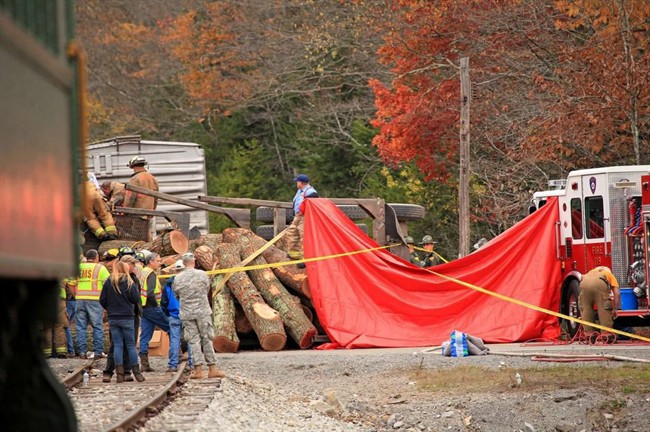 In this photo provided by the Inter-Mountain, crews work at the site where a truck carrying logs down Cheat Mountain on U.S. Route 250 crashed into the side of a train taking passengers on a scenic tour in rural Randolph County, W.Va., on Friday, Oct. 11, 2013. 