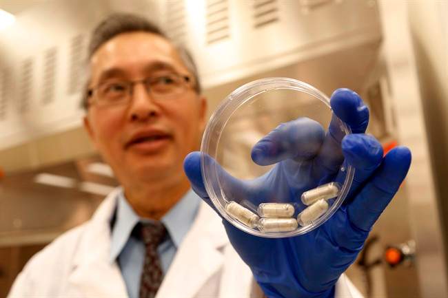 Dr. Thomas Louie, an infectious disease specialist at the University of Calgary, holds a container of stool pills in triple-coated gel capsules in his lab in Calgary, Alberta, Canada on Thursday, Sept. 26, 2013. (AP Photo/The Canadian Press, Jeff McIntosh)