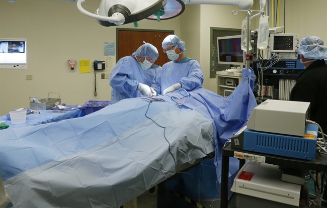 Dr. Keith Smith, right, an anesthesiologist who started Surgery Center of Oklahoma, looks on as Dr. Don McGinnis, left, and physician's assistant Steve Popielec, right, perform a surgery at the center in Oklahoma City, Thursday, Oct. 10, 2013