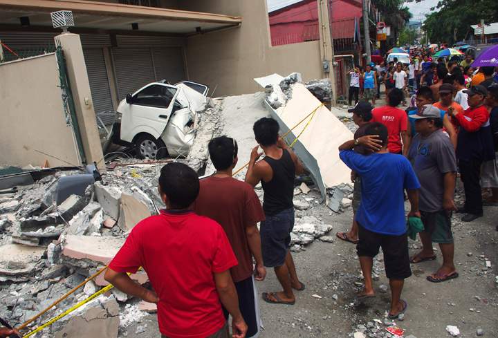 People look at a collapsed building in Cebu City, Philippines after a major 7.2 magnitude earthquake struck the region on October 15, 2013. (Photo credit: Getty Images)