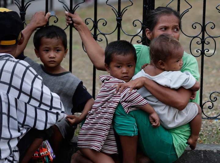 Residents sitting in the open ground cling to a railing following an aftershock from the 7.2-magnitude earthquake that hit Cebu city in central Philippines Tuesday, Oct. 15, 2013. (Photo credit: The Canadian Press)