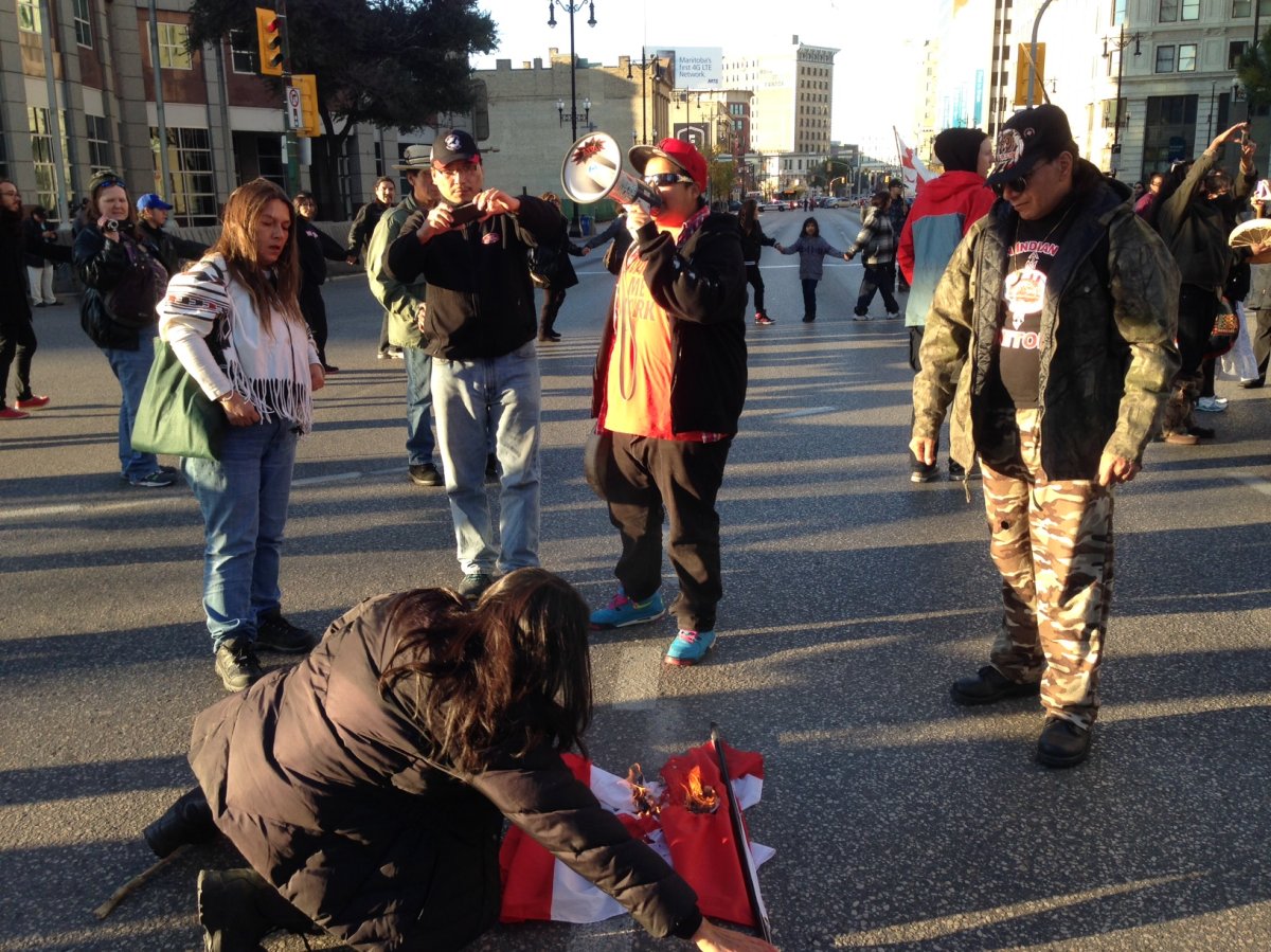 Protesters burn a flag at Portage and Main in Winnipeg on Thursday.