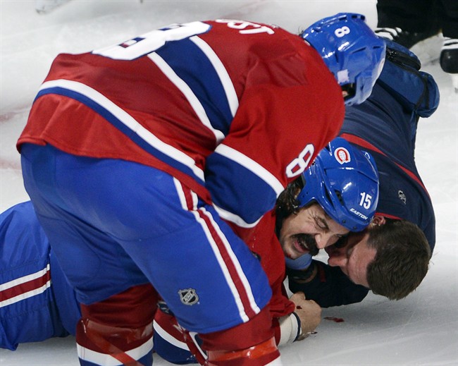 Montreal Canadiens winger George Parros (15) is treated by medical staff as teammate Brandon Prust looks on after he hit his head on the ice during a fight with Toronto Maple Leafs right wing Colton Orr during third period NHL action Tuesday, October 1, 2013 in Montreal. Parros was released from hospital on Wednesday, Oct. 2, 2013. 