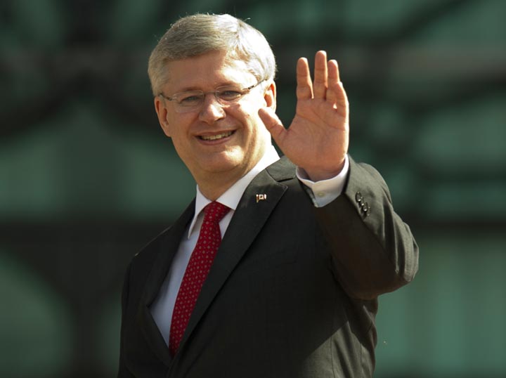 Prime Minister Stephen Harper waves during a photo call at the top steps of the prime minister's office in Putrajaya on October 6, 2013. 