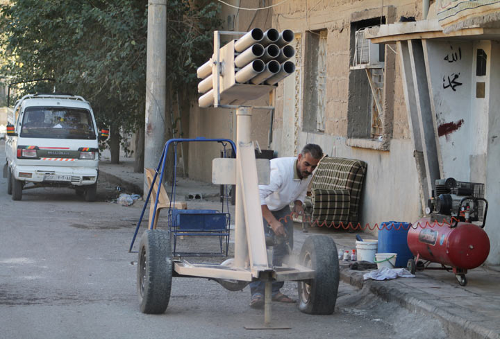 A man paints a homemade multi-rocket launcher in the Jubaila neighbourhood of Syria's northeastern city of Deir Ezzor on October 11, 2013.