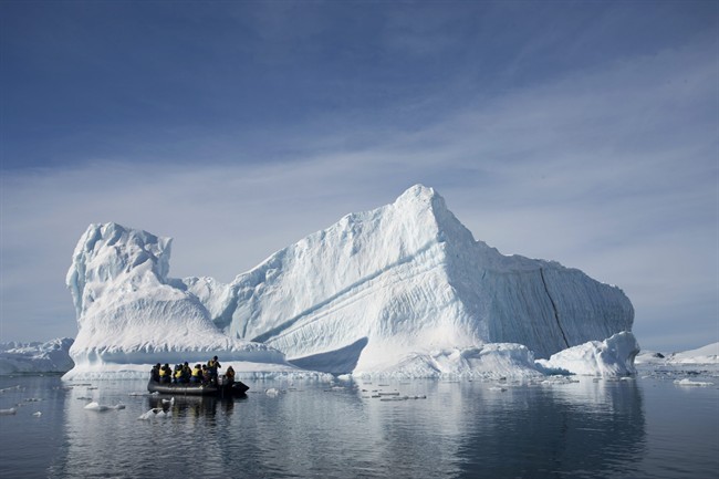An inflatable boat carries tourists past an iceberg along the Antarctic Peninsula.