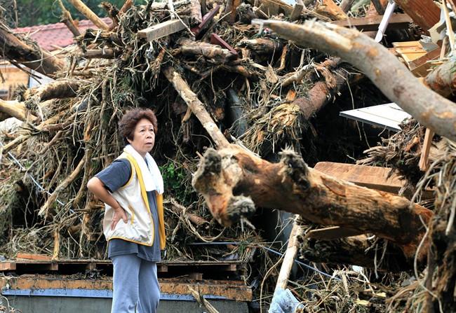 A woman looks at the aftermath of landslides in the rubble of smashed houses in Oshima after a powerful typhoon hit Izu Oshima island, about 120 kilometres south of Tokyo Wednesday morning, Oct. 16, 2013. 