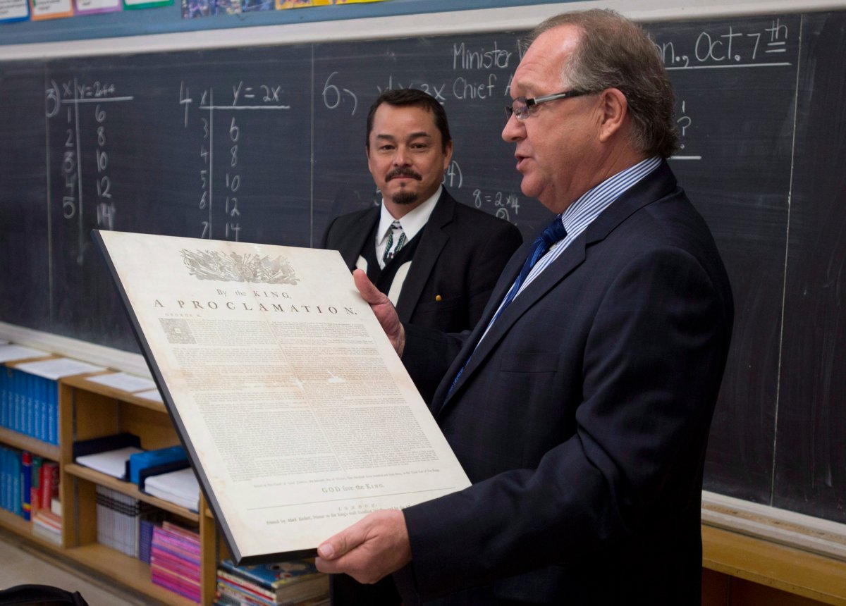 Assembly of First Nations National Chief Shawn Atleo looks on as Aboriginal Affairs and Northern Development Minister Bernard Valcourt holds a copy of the Royal Proclomation issued 250 years ago as they visit a Grade 7 class at a school in Ottawa, Monday October 7, 2013 in Ottawa. THE CANADIAN PRESS/Adrian Wyld.