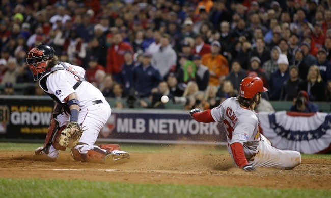 St. Louis Cardinals' Pete Kozma scores on a sacrifice fly as Boston Red Sox catcher Jarrod Saltalamacchia can't handle the throw during the seventh inning of Game 2 of baseball's World Series Thursday, Oct. 24, 2013, in Boston. (AP Photo/Matt Slocum).