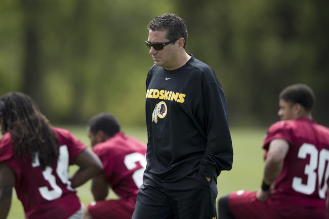 In this photo taken May 5, 2013, Washington Redskins owner Dan Snyder walks by players during a rookie minicamp practice session at Redskins Park in Ashburn, Va.