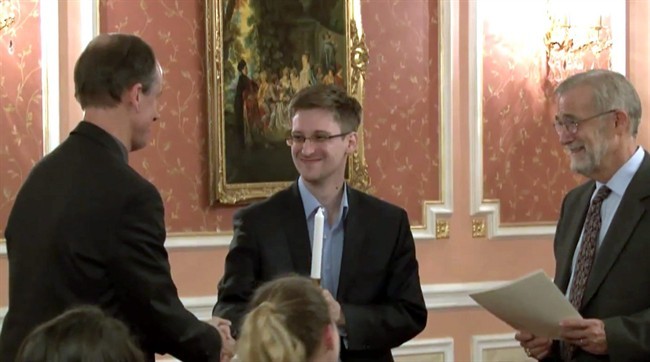 In this image made from video released by WikiLeaks on Oct. 11, 2013, former National Security Agency systems analyst Edward Snowden, center, receives the Sam Adams Award in Moscow, Russia. 