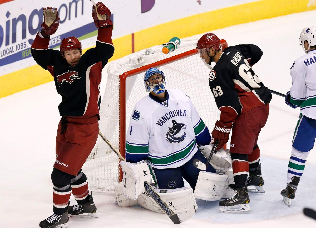 Phoenix Coyotes' David Moss, left, and Mike Ribeiro (63) celebrate a goal by teammate Shane Doan, as Vancouver Canucks' Roberto Luongo (1) kneels dejectedly on the ice. (AP Photo/Ross D. Franklin).